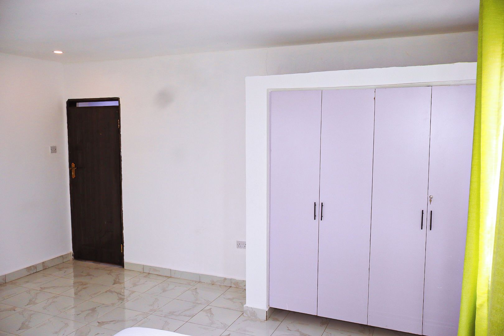 Ein Zimmer mit geschlossener Tür, einem Schrank mit zwei Türen und einem Fliesenboden.