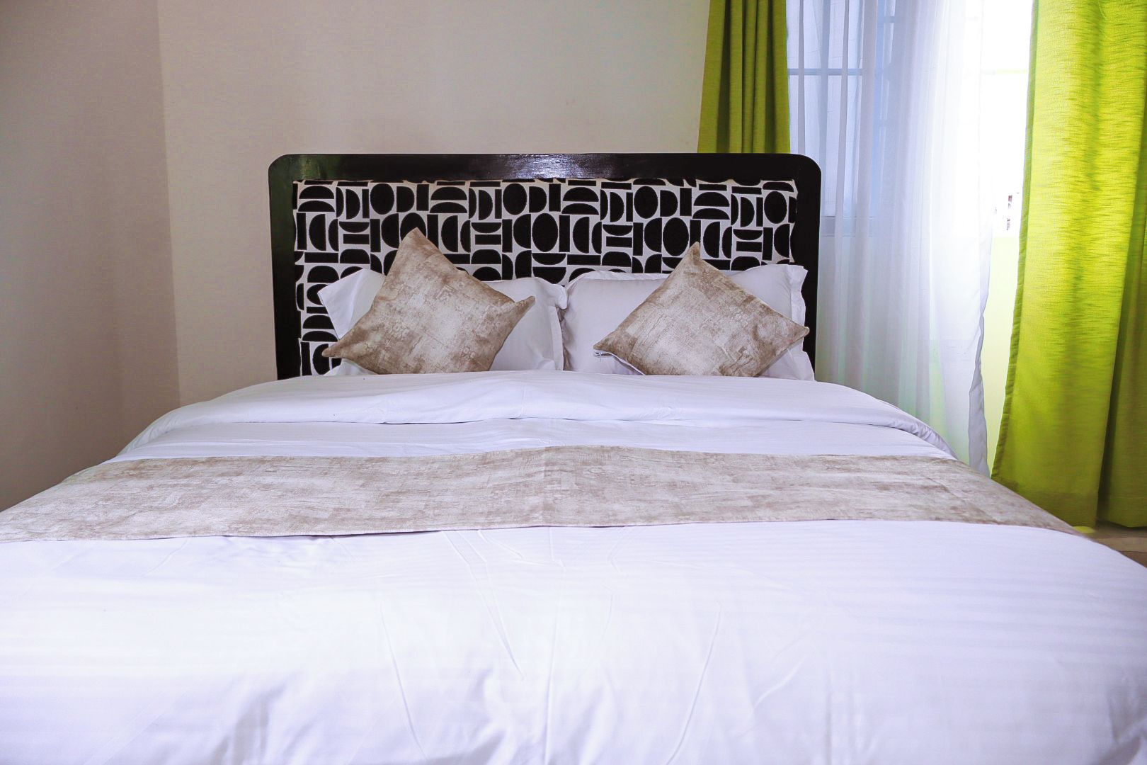 A bed with a patterned headboard, white bedding, and two pillows.