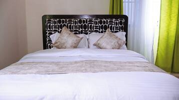 A bed with a patterned headboard, white bedding, and two pillows.