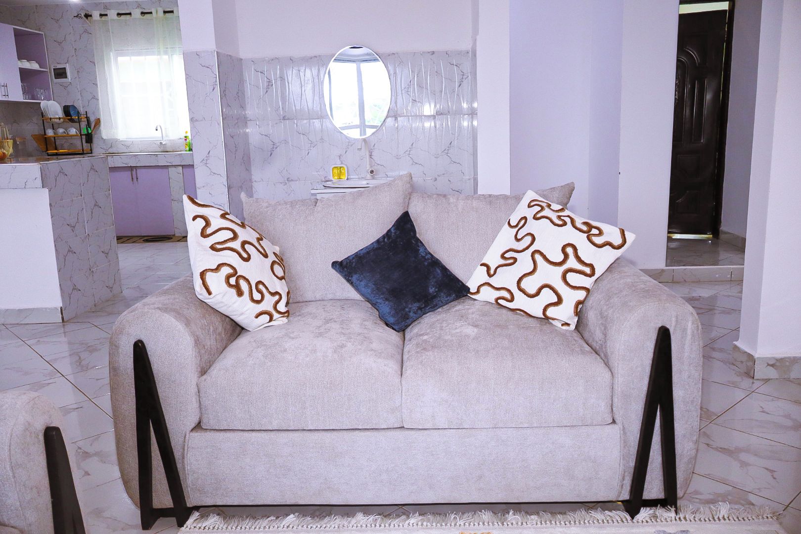 A living room with a sofa, a coffee table, and a kitchen area in the background.
