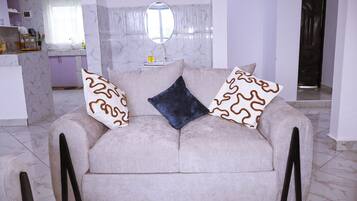 A living room with a sofa, a coffee table, and a kitchen area in the background.