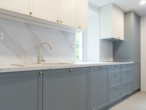 A modern kitchen with grey cabinets, a white marble countertop, and a stainless steel faucet. - Villa Acquarossa 1736 by Interhome (Acquarossa)