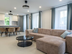 A modern living room with a sectional sofa, a round coffee table, and a dining area with chairs. - Villa Acquarossa 1736 by Interhome (Acquarossa)