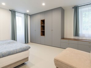 A bedroom with two beds, a wardrobe, a small shelf, and a window with curtains. - Villa Acquarossa 1736 by Interhome (Acquarossa)