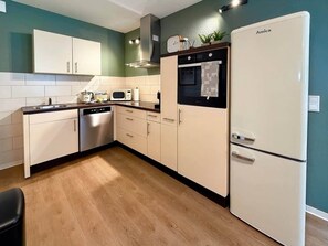 A kitchen with white cabinets, a microwave, a stove, and a refrigerator. - New designer apartment with a terrace in the Old Town (Nordhausen)