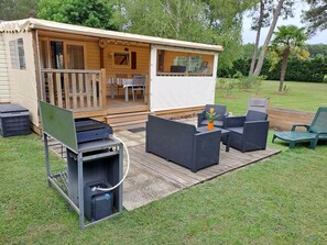 Une maison mobile dotée d’une terrasse, de mobilier d’extérieur et d’un barbecue.