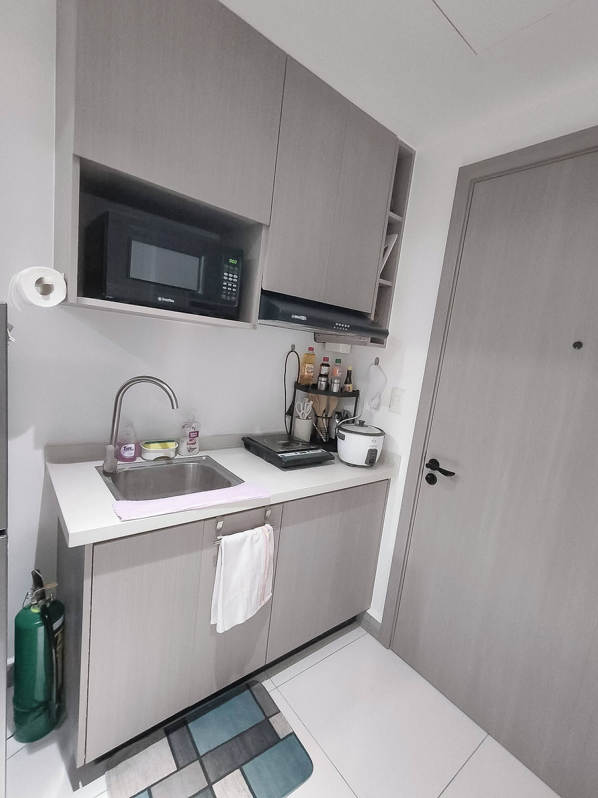 A compact kitchen with a microwave, sink, and a small countertop area with various items.