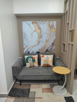 Un sofá gris con dos almohadones decorativos, una mesita redonda y una alfombra estampada.