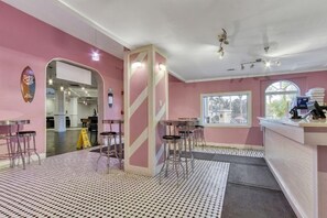 A bar area with stools, a counter, and a view through a window. - The Regal Escape W/ Lazy River | Near Disney (Davenport)