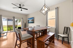 A dining area with a wooden table and chairs, a ceiling fan, and a large window with curtains. - The Regal Escape W/ Lazy River | Near Disney (Davenport)
