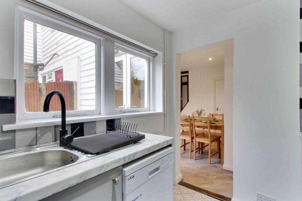 A kitchen with a window, sink, and a dining area with chairs and a table.