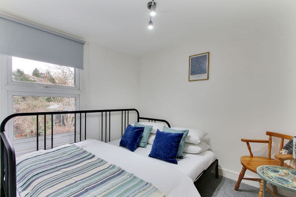 Une chambre à coucher avec un lit, une fenêtre, une chaise et une petite table.