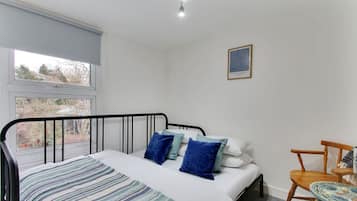 Une chambre à coucher avec un lit, une fenêtre, une chaise et une petite table.