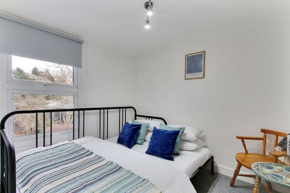 A bedroom with a bed, a window, a chair, and a small table.