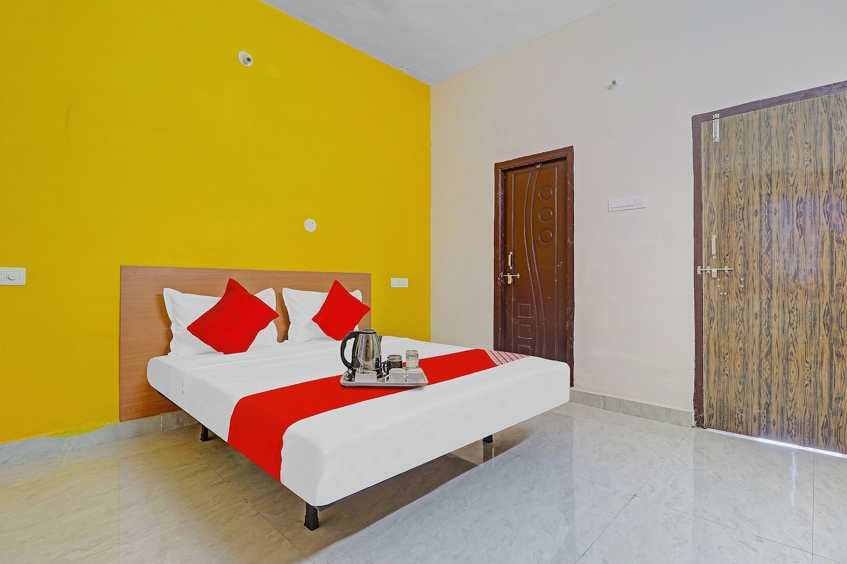 A hotel room with a bed, a wooden door, and a yellow wall.