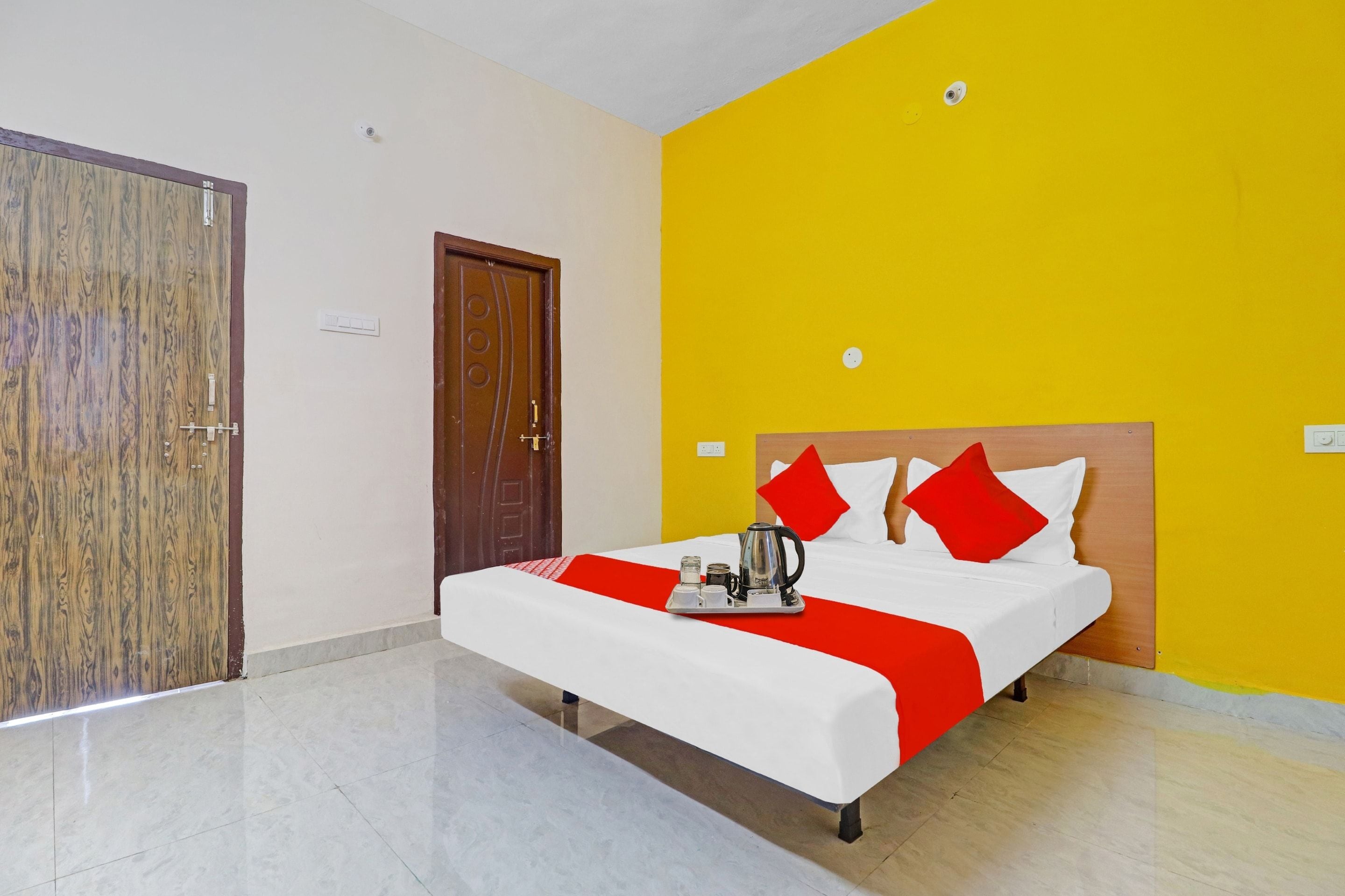 A hotel room with a bed, a wooden door, and a yellow wall.