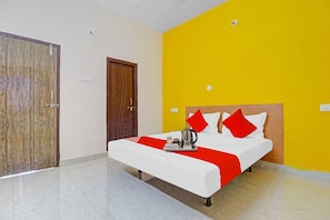 A hotel room with a bed, a wooden door, and a yellow wall. - Super Hotel O Elite Stay (Hyderabad)
