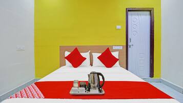 A hotel room with a bed, a tray with a kettle and cups, and a door with a circular handle.
