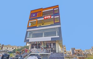 Un edificio de varios pisos con un llamativo letrero de 'OYO Rooms'.