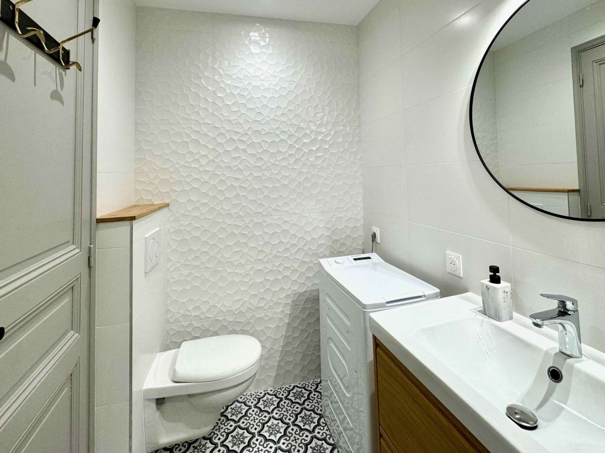 Un baño moderno con inodoro, lavamanos y espejo.