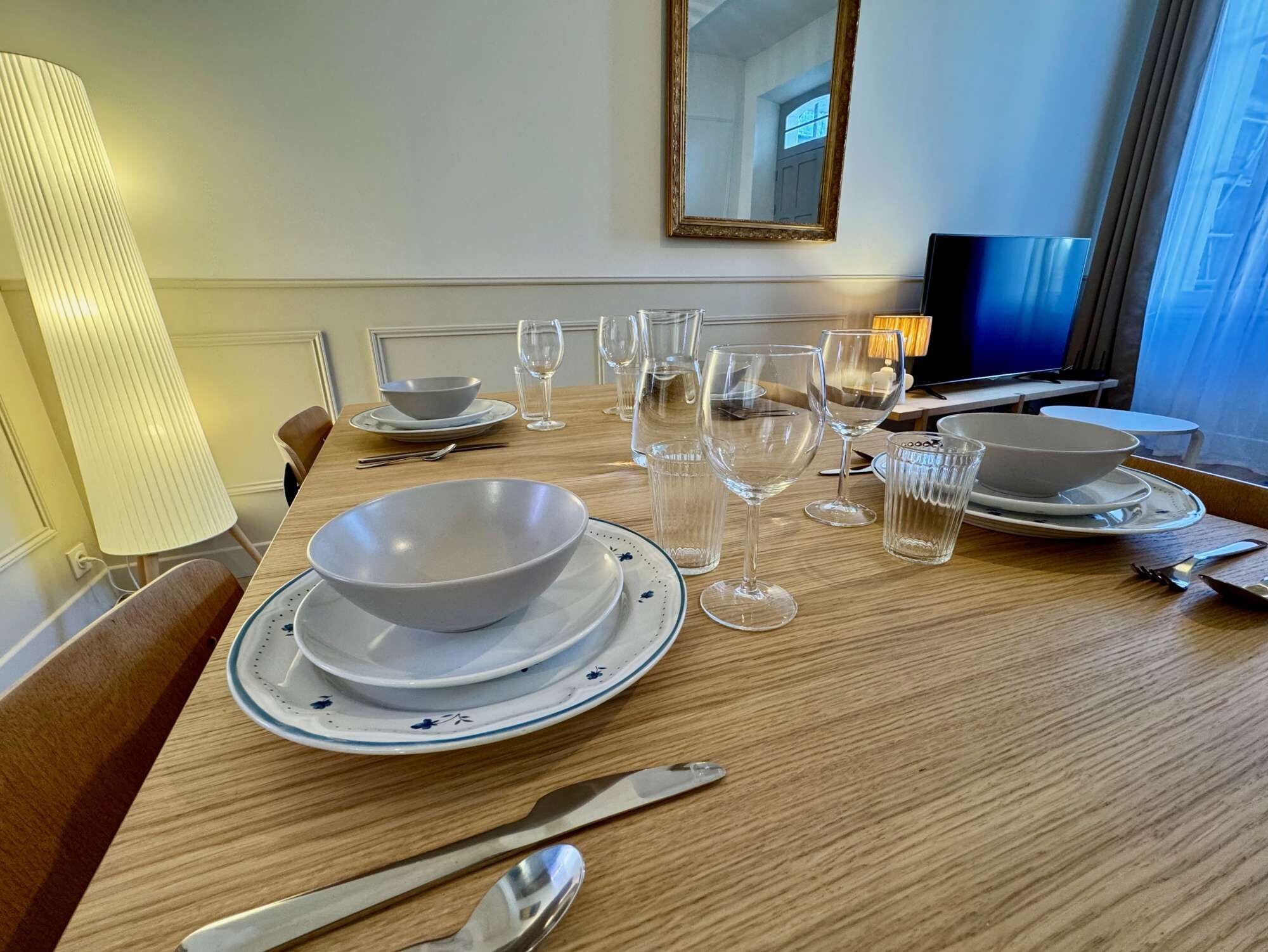A hotel dining table set with plates, bowls, wine glasses, and cutlery.