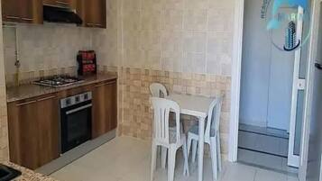 A kitchen with a gas stove, oven, and white chairs at a table.