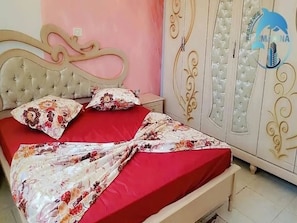 A bedroom with a bed, a nightstand, and a wardrobe.