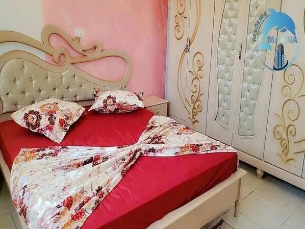 A bedroom with a bed, a nightstand, and a wardrobe. - Chott Mariem Apartment Sousse (Chott Mariem)