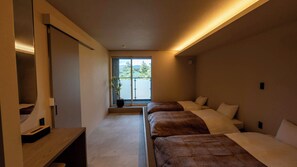 A modern hotel room with a large window, a bed with a brown blanket, a bedside table, and a built-in shelf. - NUA Yamanakako (Yamanakako)