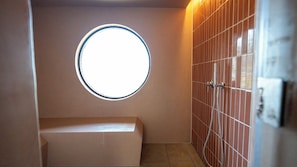 A bathroom with a round window, a bench, and tiled walls. - NUA Yamanakako (Yamanakako)