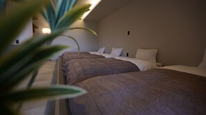 A hotel room with two beds, a bedside table, a lamp, and a plant. - NUA Yamanakako (Yamanakako)