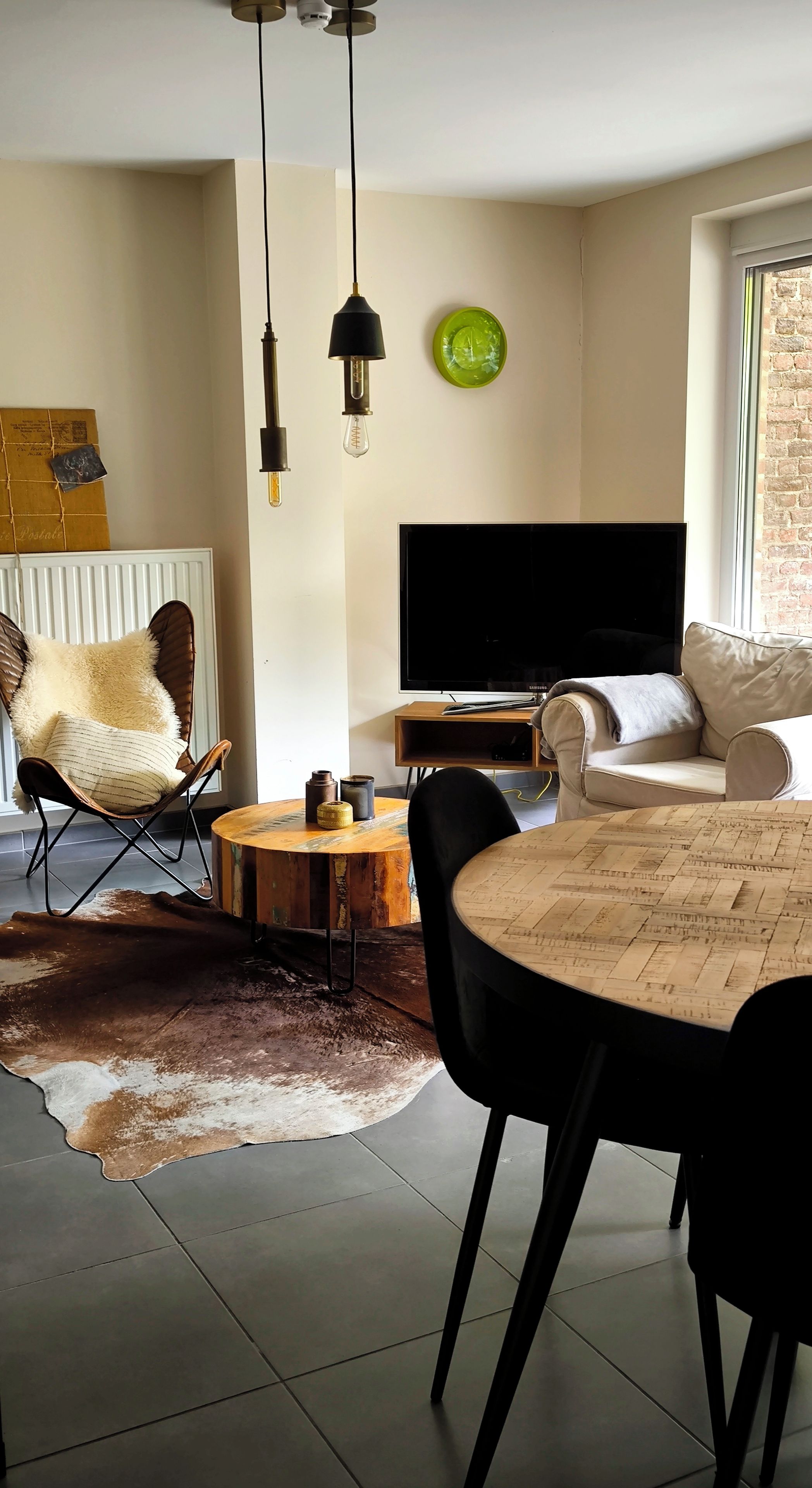 Un salon moderne avec un téléviseur, un canapé en cuir et une table à manger avec des chaises.