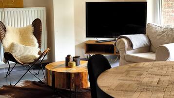 Un salon moderne avec un téléviseur, un canapé en cuir et une table à manger avec des chaises.