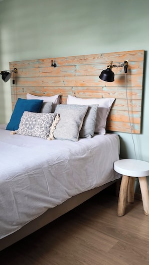 A bed with a striped bedspread, multiple pillows, and a wooden headboard with a telephone.