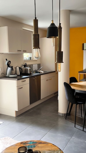 A modern kitchen with white cabinets, a sink, and a dining area with a table and chairs.