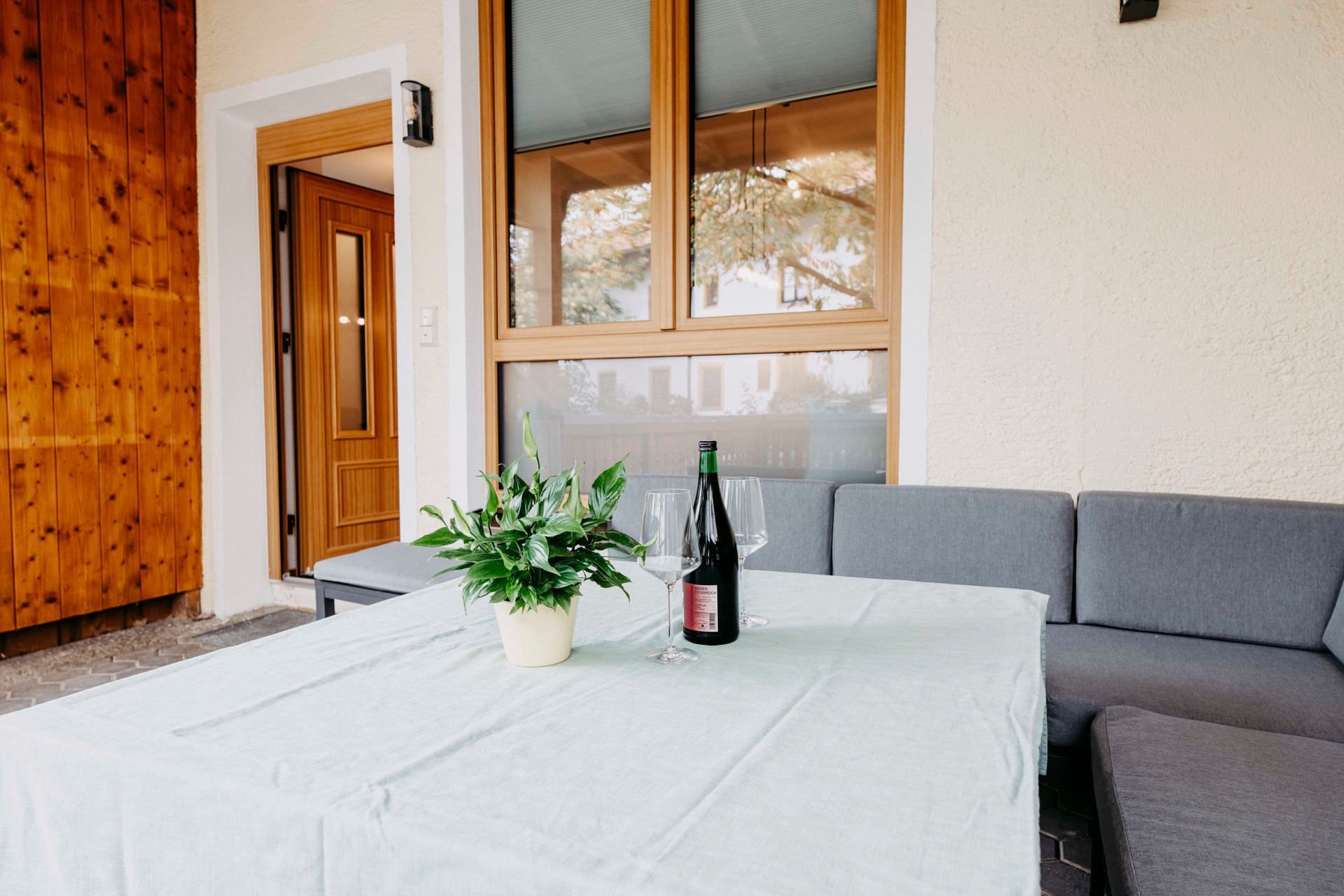 Ein Tisch mit weißer Tischdecke, einem Blumentopf, einer Weinflasche und zwei Weingläsern.
