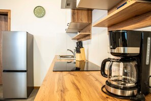 Eine Küche mit einem Edelstahl-Kühlschrank, einer Holz Arbeitsplatte, einer Kaffeemaschine und einer Wanduhr.