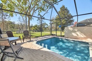 A swimming pool with a covered patio area, outdoor seating, and a view of the surrounding landscape. - Windsor Palms - 29539 (Kissimmee)