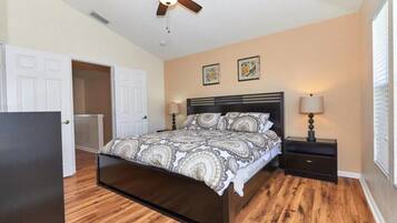 A bedroom with a bed, nightstands, a ceiling fan, and a door.