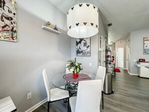A dining area with a round table, chairs, a potted plant, and a Mickey Mouse themed light fixture. - Windsor Palms - 29551 (Kissimmee)