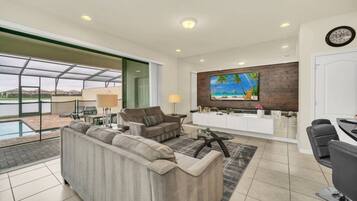 A modern living room with a sofa, a coffee table, and a TV mounted on a wooden wall.