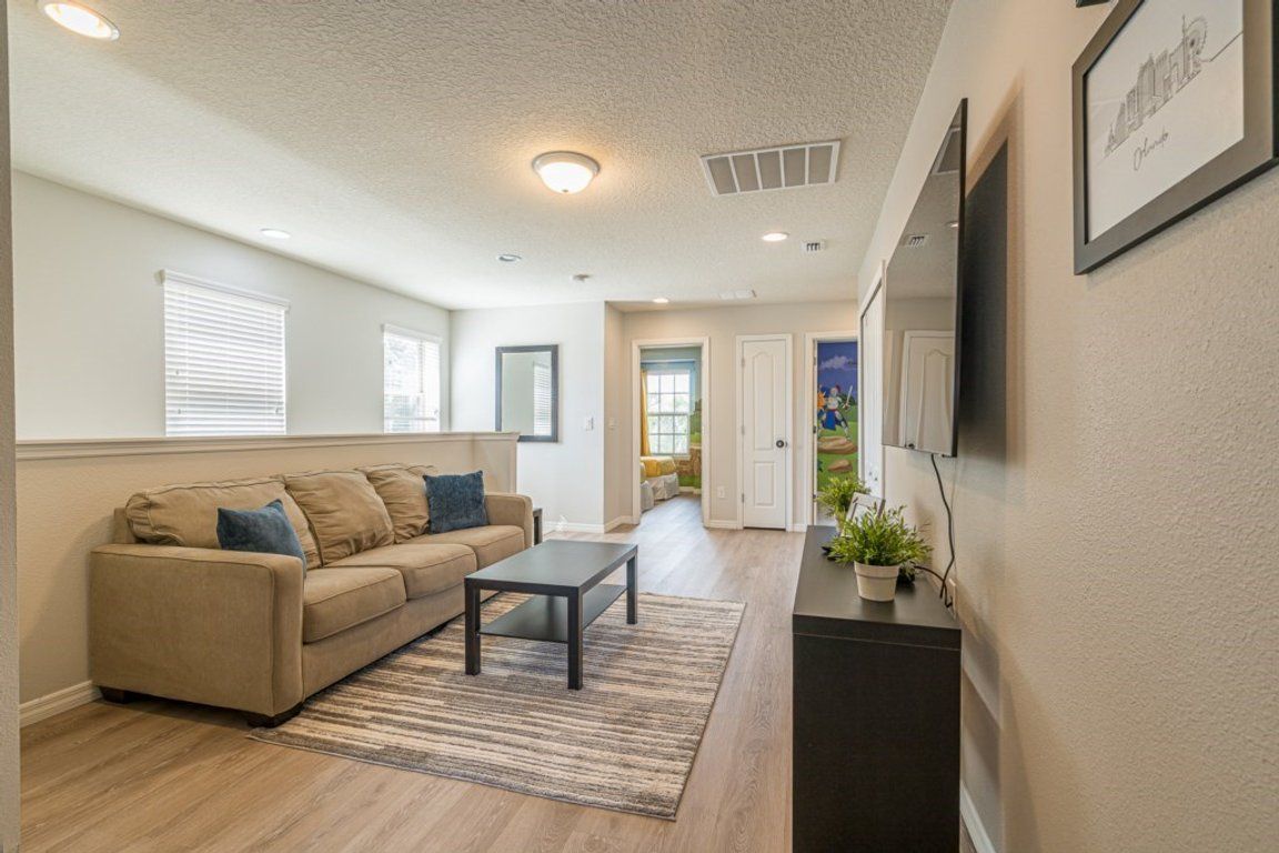 A living room with a sofa, a coffee table, and a TV mounted on the wall.