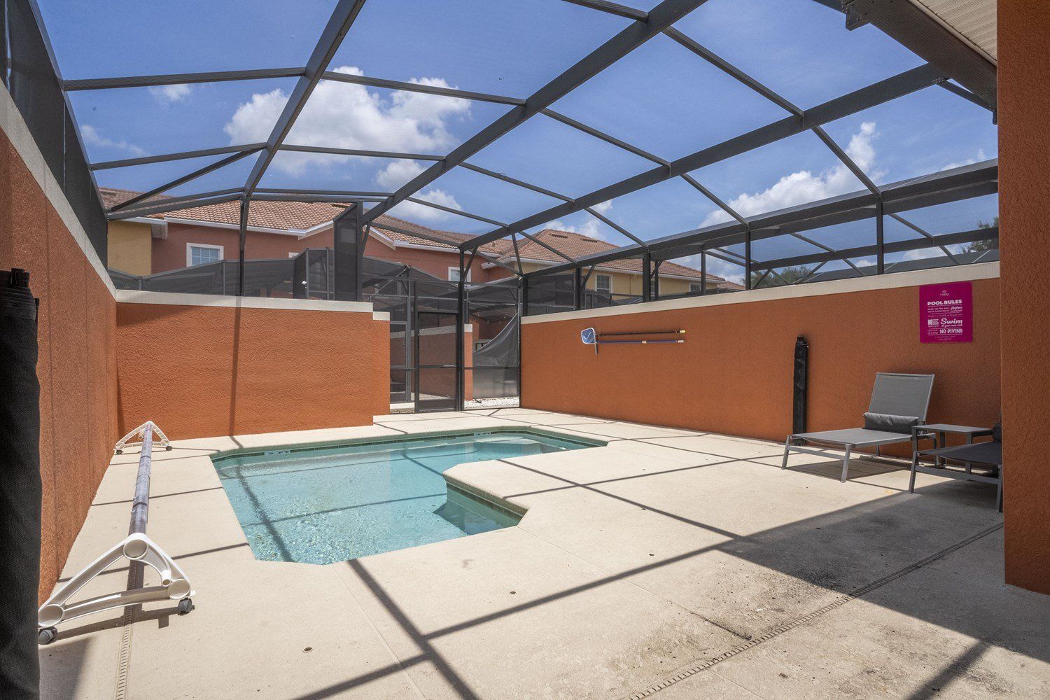Una piscina interior con techo de vidrio, una escalera de piscina y sillas de descanso.
