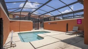 Una piscina interior con techo de vidrio, una escalera de piscina y sillas de descanso.