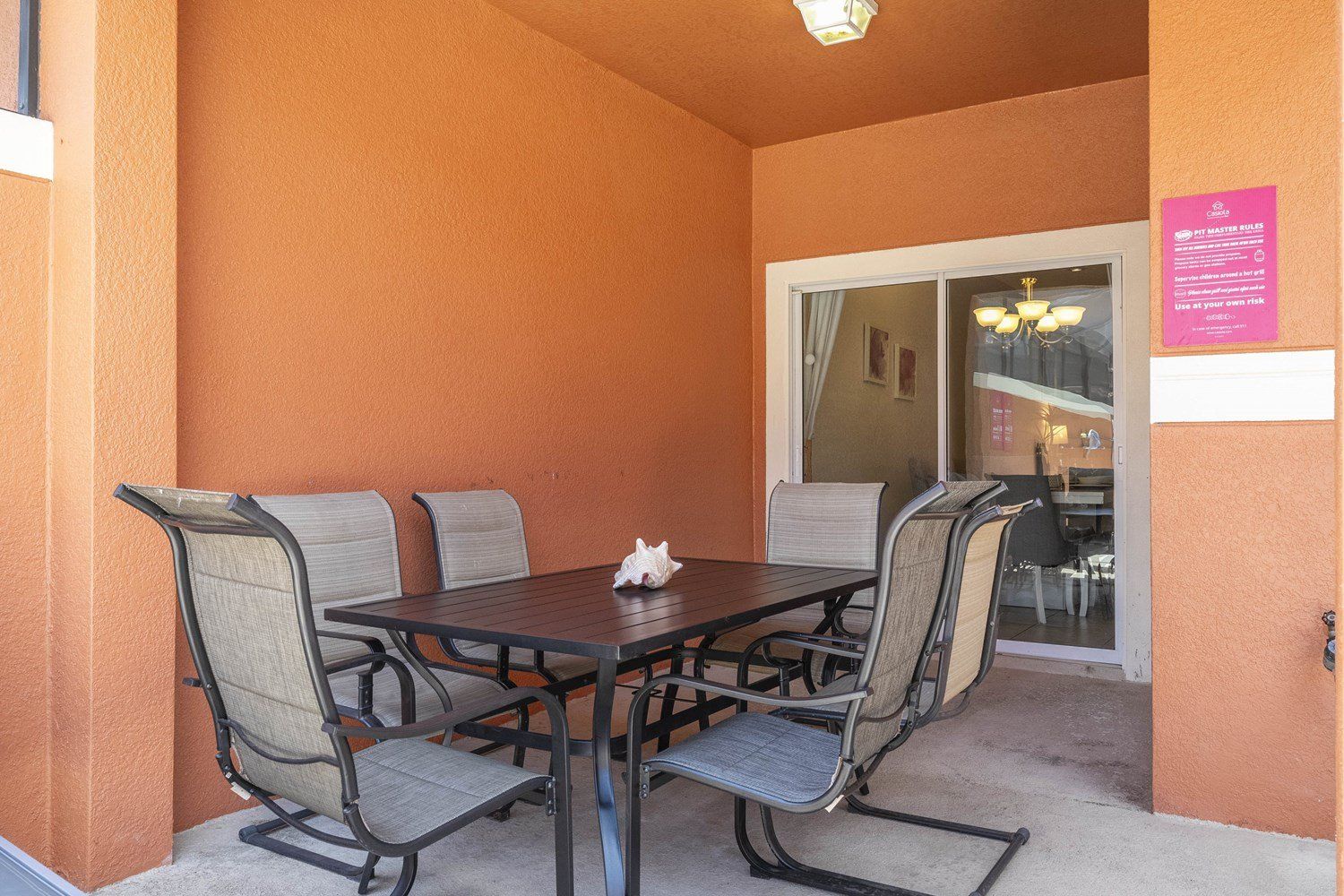 Un coin repas avec une table et quatre chaises, une porte avec un panneau de verre et un panneau indicateur sur le mur.