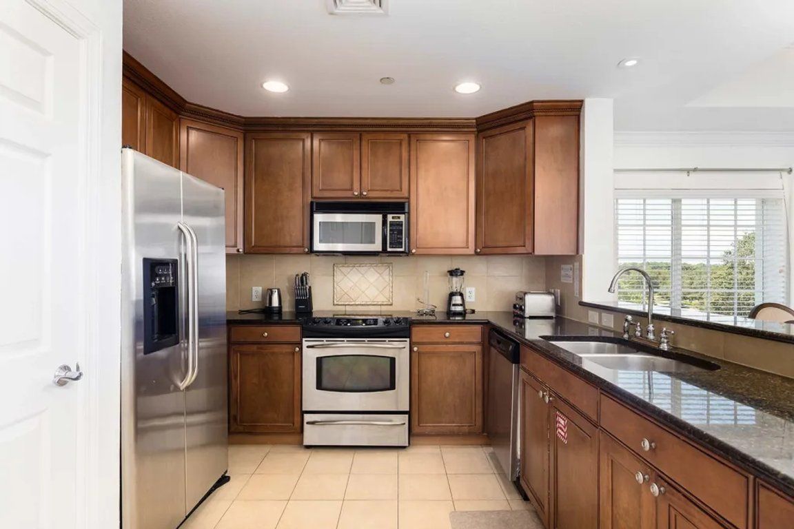 A kitchen with wooden cabinets, stainless steel appliances, and a large window.