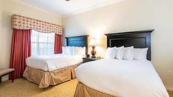 Une chambre d’hôtel avec deux lits, une table de chevet avec une lampe et une fenêtre avec des rideaux rouges.