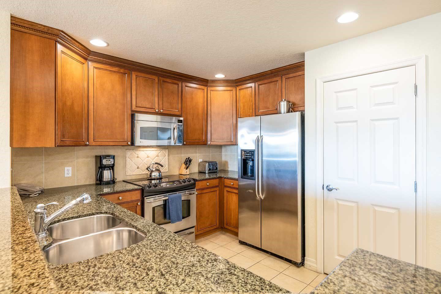 A kitchen with wooden cabinets, stainless steel appliances, granite countertops, and a double sink.