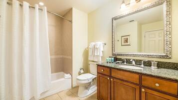 Une salle de bain équipée d’une douche, de toilettes, d’un lavabo et d’un grand miroir.