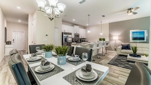 A modern dining area with a white table set for four, surrounded by chairs. - Storey Lake - 6036 (Kissimmee)